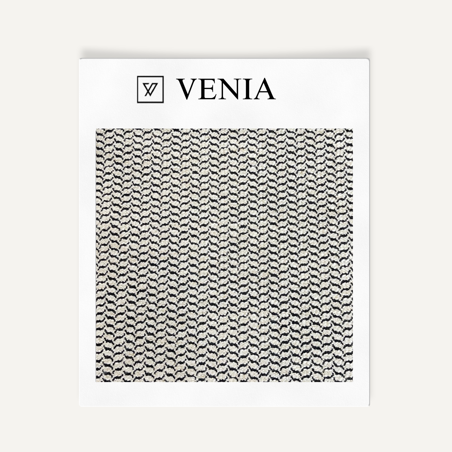 Textile sample with 'VENIA' branding and a black and white pattern on a white background