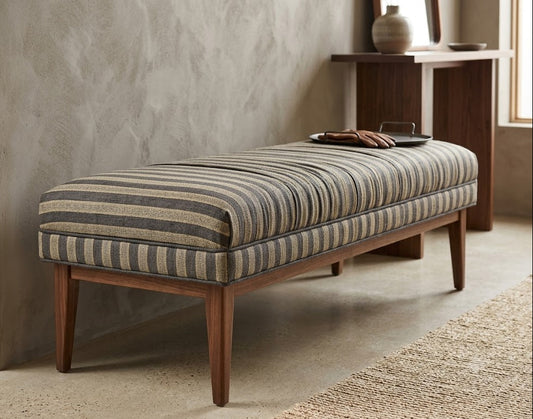 Striped bench with wooden legs against a textured wall.