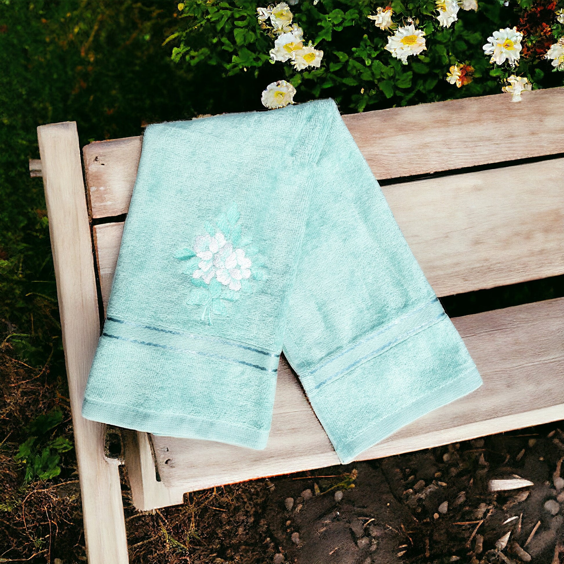 aqua green hand towel with one flower embroidered on it