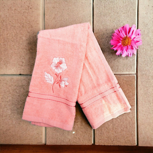 Pink hand towel with one flower embroidered on it