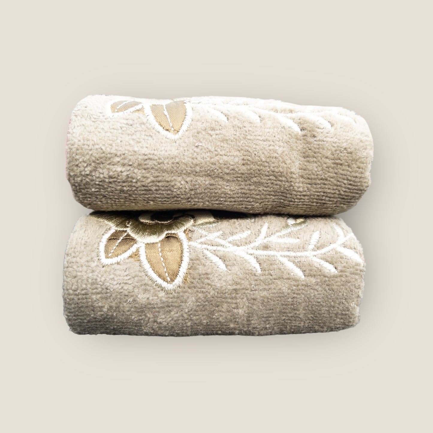 Two olive green folded hand towels with big embroidered flowers made on it, stacked