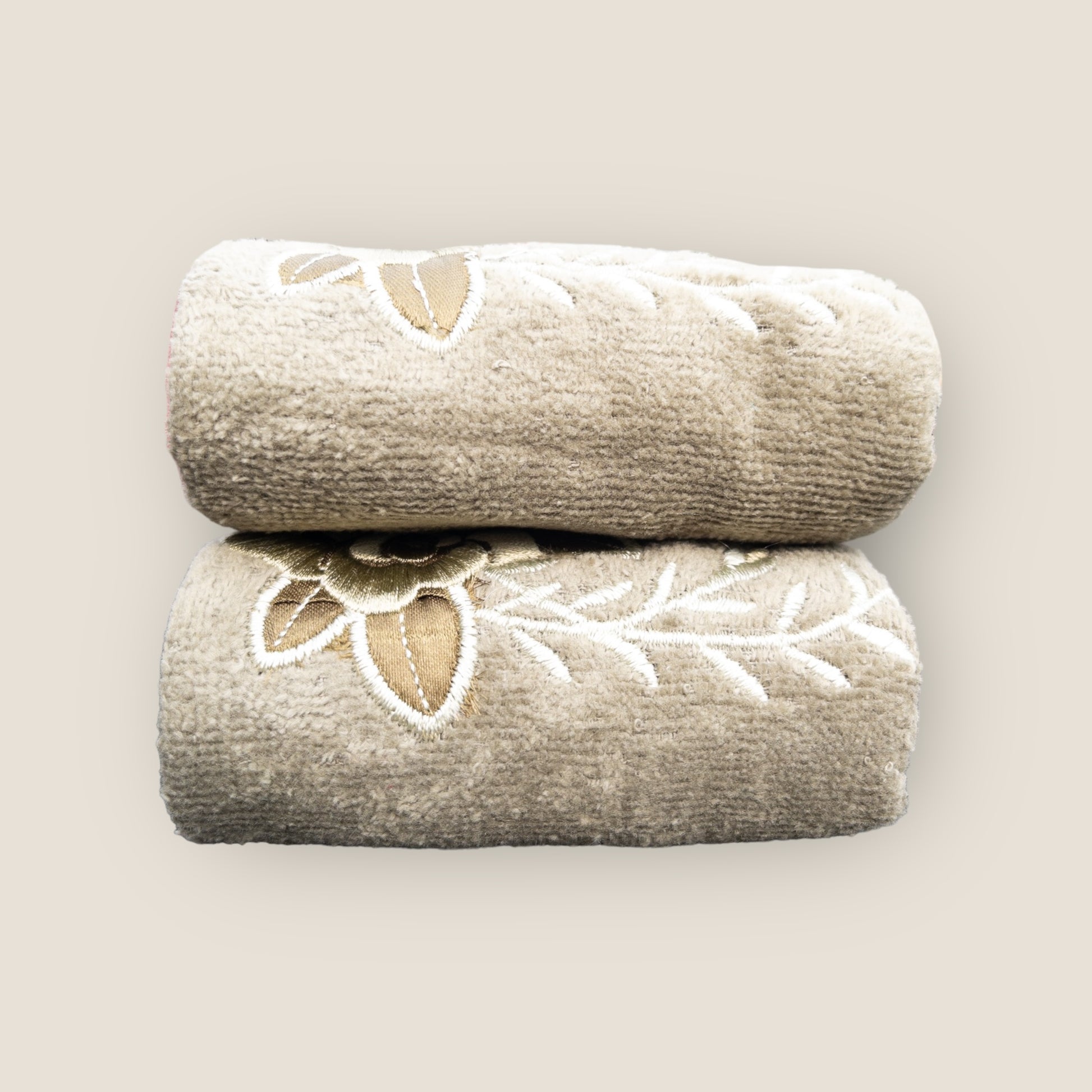 Two olive green folded hand towels with big embroidered flowers made on it, stacked