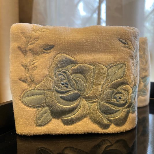 Folded white hand towel with big light blue embroidered flowers made on it
