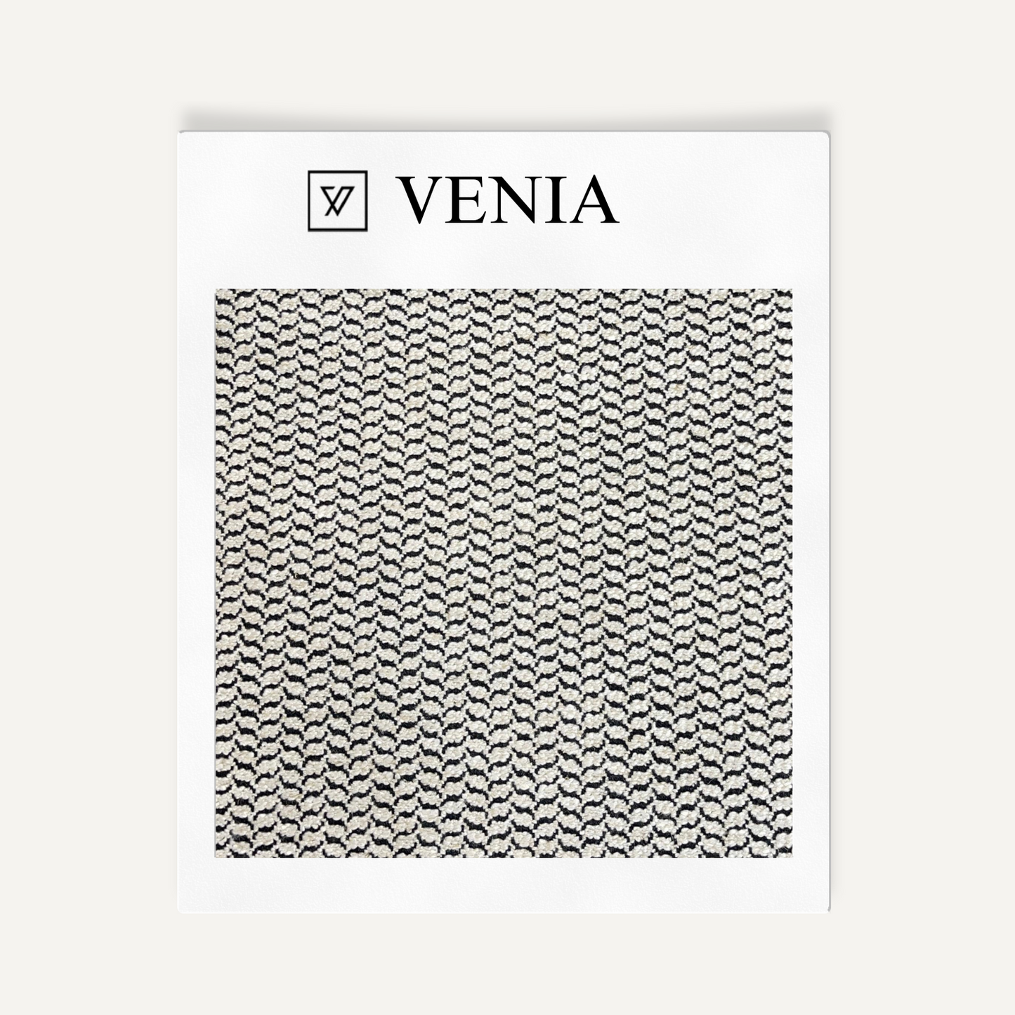 Textile sample with 'VENIA' branding and a black and white pattern on a white background