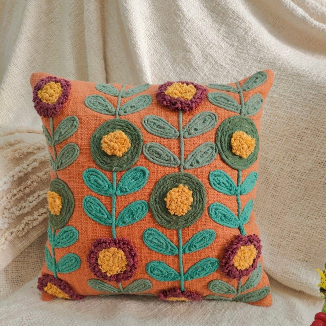 orange boho cushion cover with beautiful threadwork, placed on a white cloth
