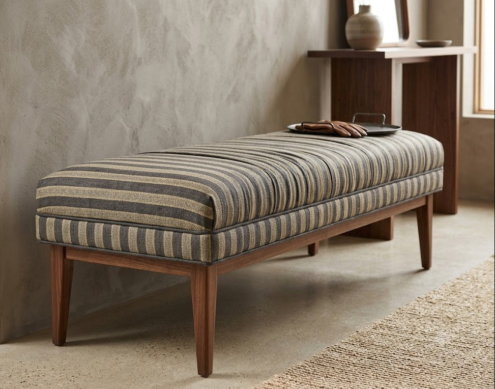 Striped bench with wooden legs against a textured wall.