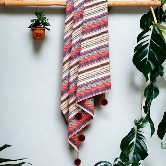 a multi color sofa throw hanging from a rod