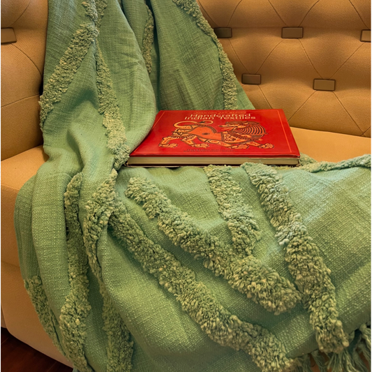 a green tufted throw styled on a sofa