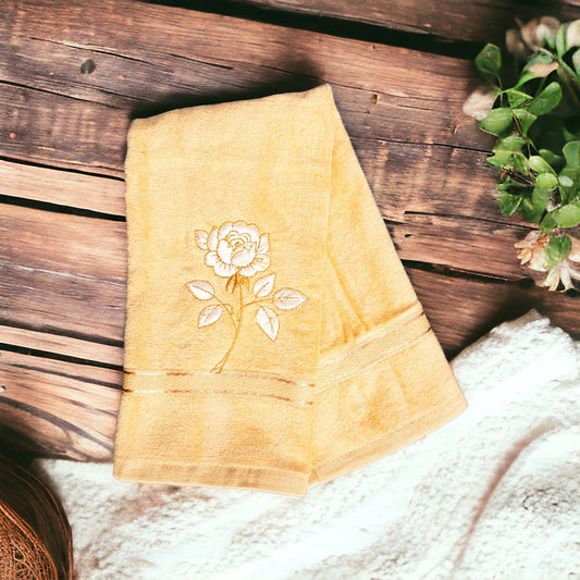 Yellow hand towel with one flower embroidered on it