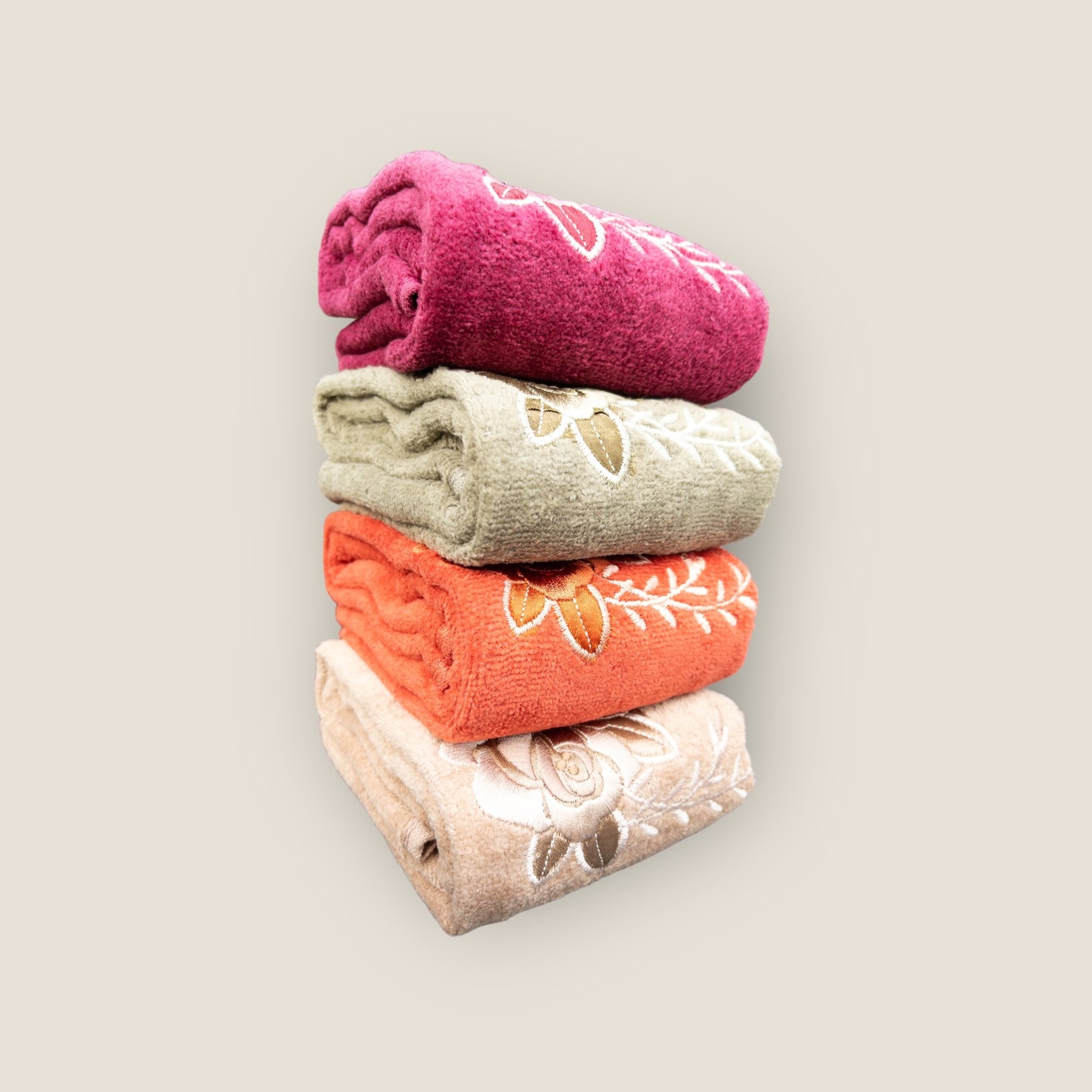 Four brightly colored hand towels with floral embroidery, stacked on top of each other