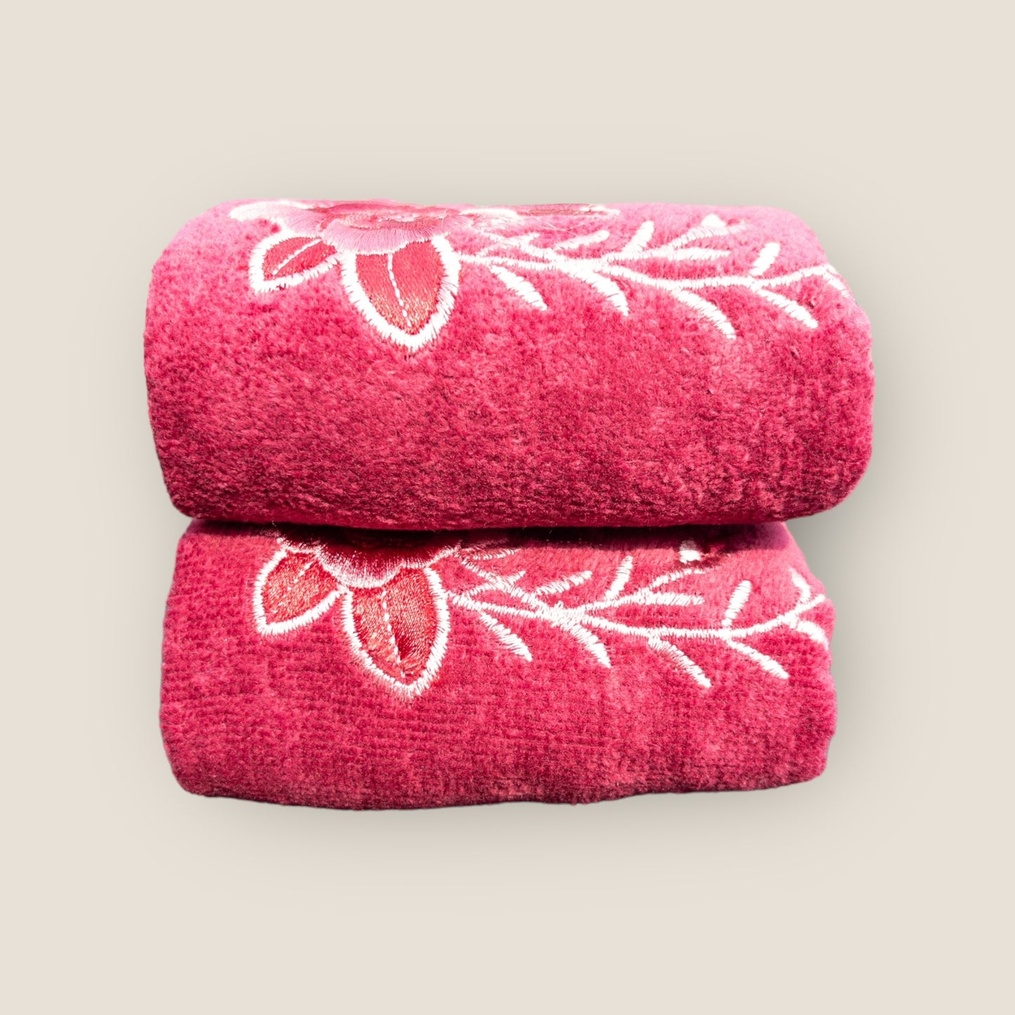 Two folded pink hand towels with big embroidered flowers made on it